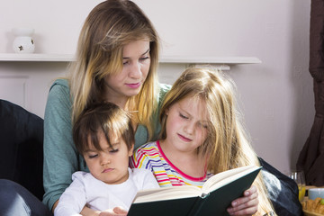 Tired mother reading book to kids
