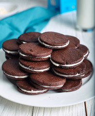 Chocolate sandwich cookies with cream filling on wood background.