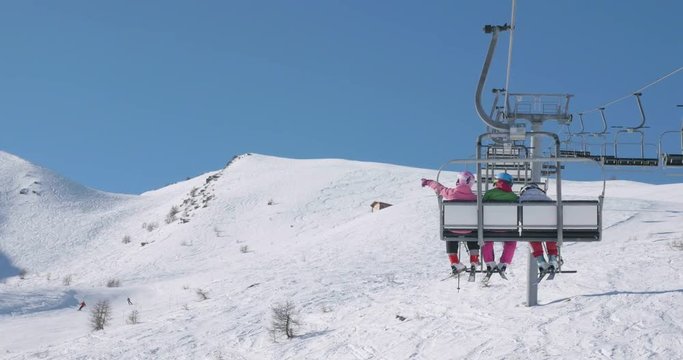 Teen Girl showing a ski slope to their firend while riding a chair lift
