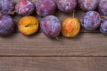 frame of plums on the old wooden background