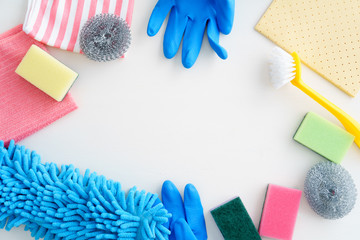 Collection of pastel-coloured cleaning supplies on white background with copyspace