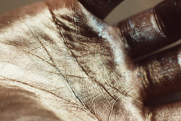 Close-up photo of golden human hand. Patterns on painted palm with gold dust. Luxury design of greasepaint, ceremonial body art