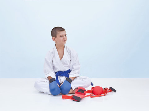 Karate sportsman sits near a karate outfit