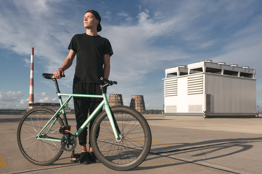 Boy in cap with eyes closed and face in sunlight holding his bike
