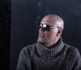 Fototapeta premium studio portrait of a bald man with glasses and a cigarette