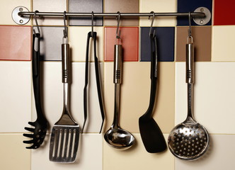 Kitchen utensils hanging on a colored  tile wall