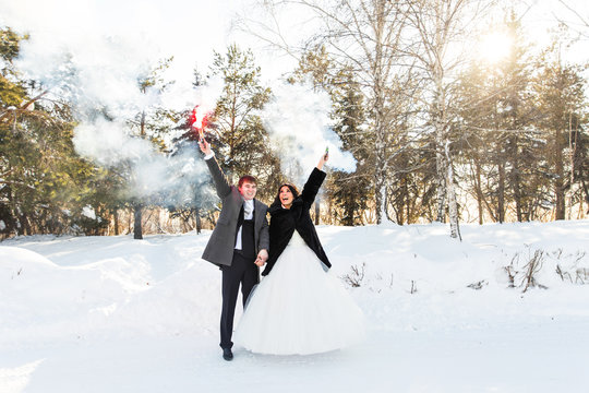 The bride and groom with smoke bombs in winter