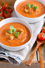 Tomato soup with cream, croutons and parsley on in a wooden tray