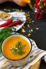 A bowl of cream soup with pumpkin on a black background, selective focus
