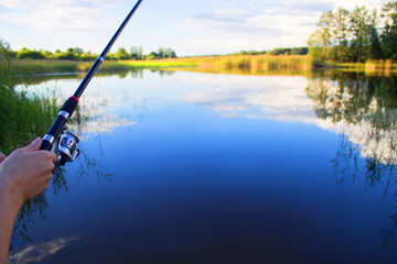 Fishing rod in hand on a background of lake