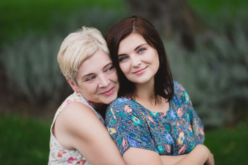 Naklejka premium Mother and adult daughter in a green park posing together