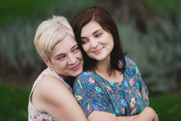 Obraz premium Mother and adult daughter in a green park posing together