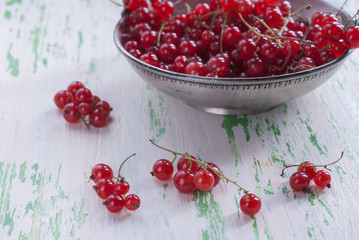 Ripe red currants in an old metal plate on wooden background.