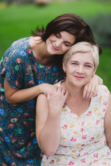Fototapeta premium Mother and adult daughter in a green park posing together