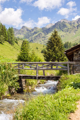 vertical mountain panorama with a wooden bridge on a creek - Pon