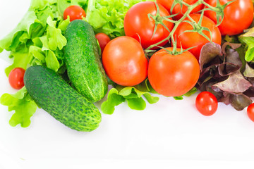 Different bright vegetables on a white background. Tomato, cucumber and lettuce.