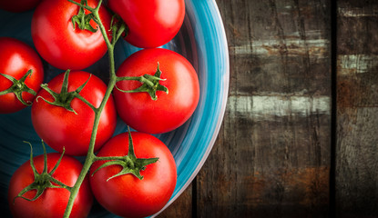 Tomatoes branch on blue plate and old rustic wooden table