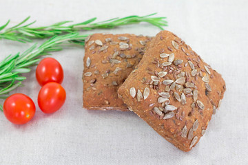 Brown bread with seeds and rosemary and tomato on table. Healthy morning breakfast.