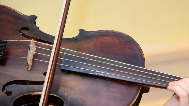 Old wooden violin with bow. Violinist plays the vintage violin. Beautiful classical music string instrument. An orchestral Symphony at the concert.