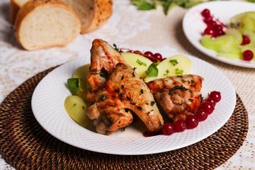 chicken wings with potatoes and cranberries on the plate, still life in the restaurant