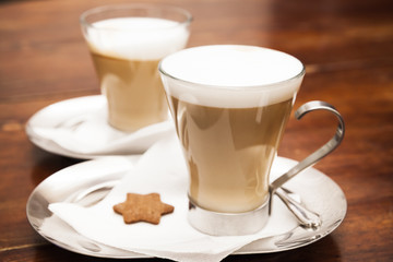 Glass mugs full of Cappuccino on wooden table