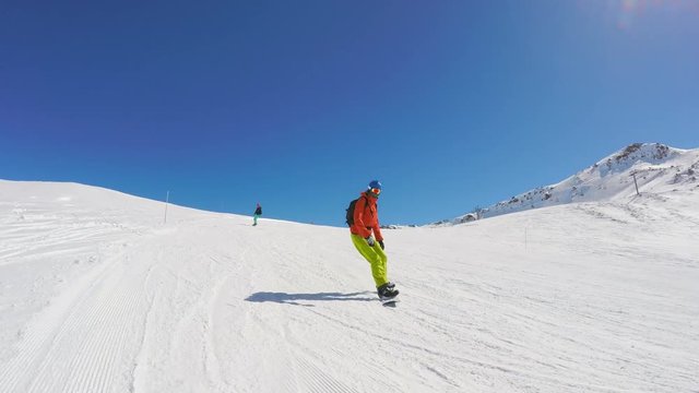 Snowboarding down a ski slope, very wide establishing shot, third person view
