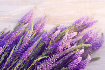 Obraz premium Summer lilac wild flowers on a light wooden background