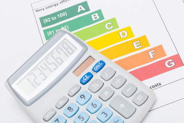 Calculator over colorful energy efficiency chart