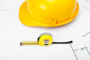 Yellow construction helmet with measure tape near it