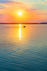 Fototapeta premium fisherman by boat fishes on lake