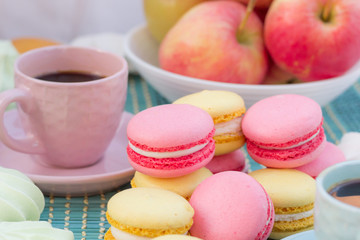 Still life of pink coffee cup, macaroon cookies and apples