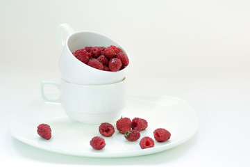 Berries raspberries in a white cup on a white background 