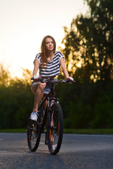 Naklejka premium girl on a bicycle at sunset
