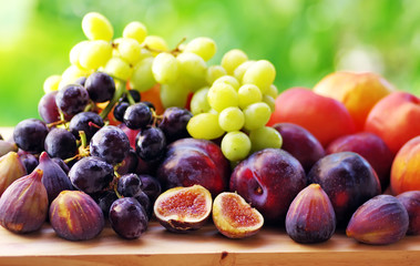 fresh ripe fruits close-up: plums, peaches, figs and grapes