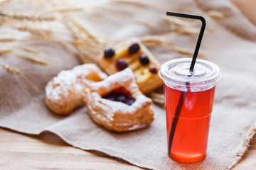 Fresh compote of dried fruits in plastic cups on rustic table with pasties. Selective focus