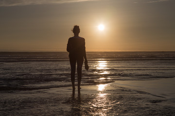 Meditative young woman watching sunset at the beach.