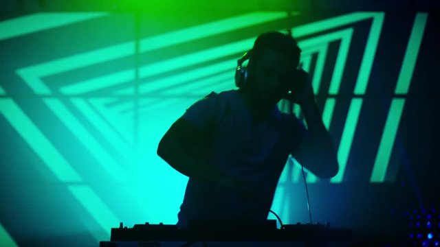 Backlit DJ Playing Music in Nightclub. Silhouette of a DJ. Bright Animation on Background. Shot on RED Cinema Camera in 4K (UHD).