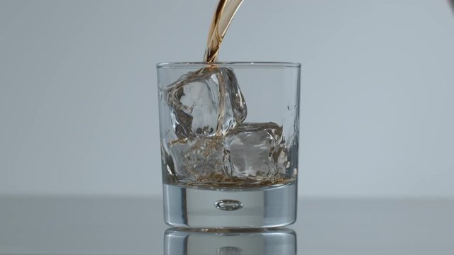 Whisky is poured over ice in slow motion