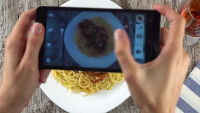 Girl is making photo with her phablet of her delicious pasta with mussels in tomato souce in a restaurant. Prores, 4K.