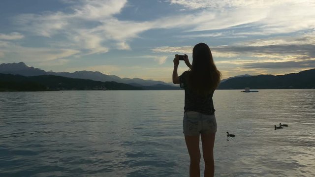 Woman photographing lake and ducks