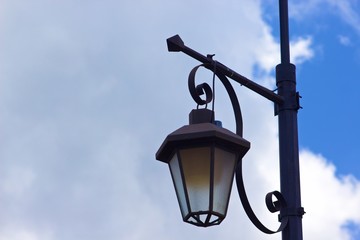 A lantern street light with a cloudy blue sky 