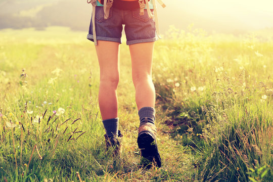young woman hiker walking on trail in grassland