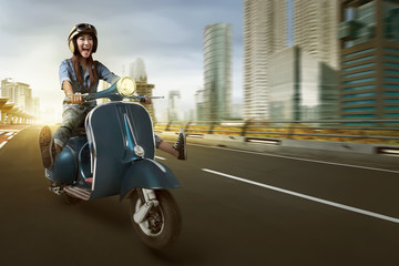 Asian woman riding scooter and wearing helmet