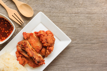 Hot Meat Dishes - Thai style fried chicken with Red Spicy Sauce and Sticky rice isolated on wooden table, Thai food