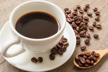 Coffee cup and coffee beans on wooden table.