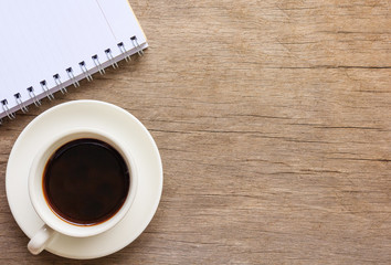 Top view and close up of old wooden desktop with notebook, smartphone and coffee cup.