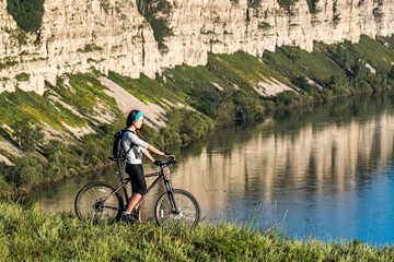 Fototapeta premium girl standing with bicycle on a background of cliff