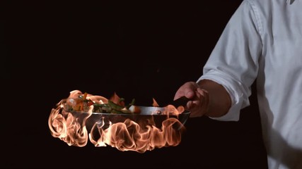 Slow motion shot of chef with flaming stir fry