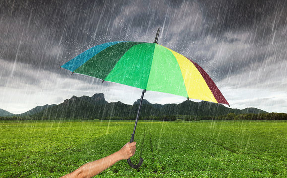 hand holding multicolored umbrella with falling rain at Khao Jee