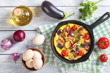 scrambled eggs, eggplant, onion and tomato in frying pan